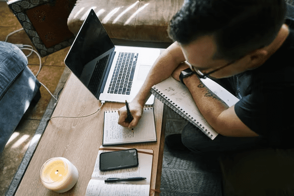 Man with laptop and notebooks, working on his content creation strategy.